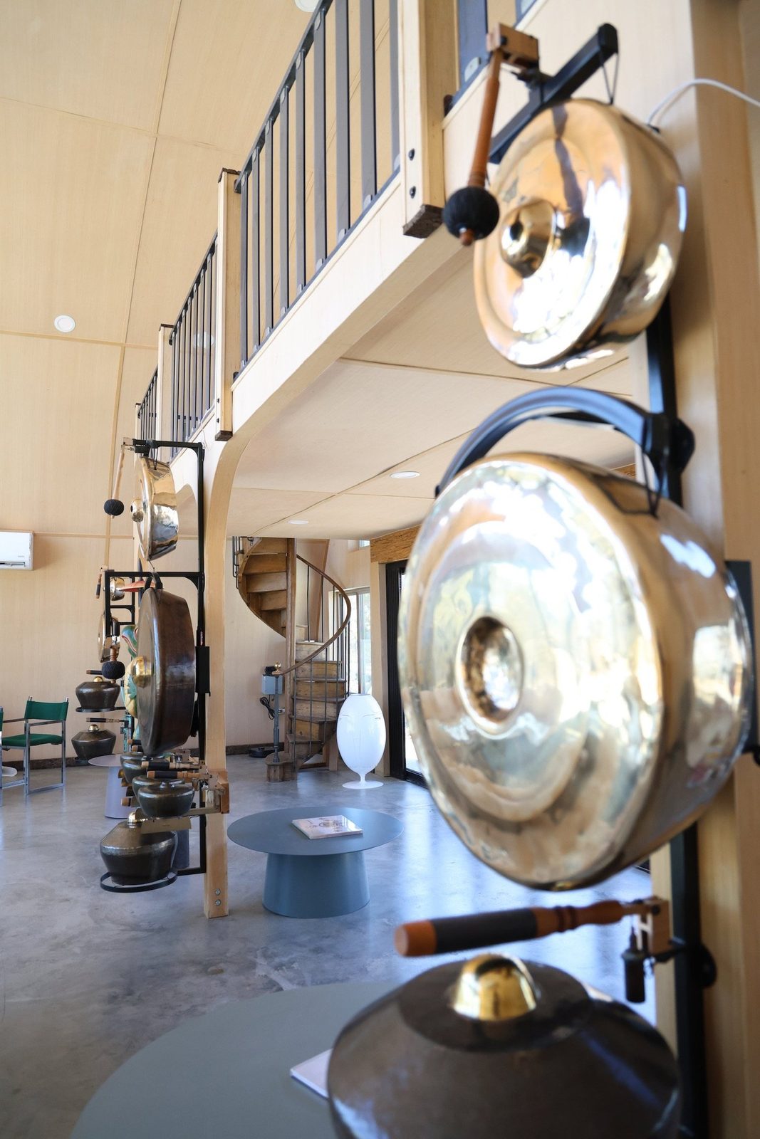 Rows of gleaming gongs with padded mallets filling the two story sound room, a wooden spiral staircase winding up to the loft