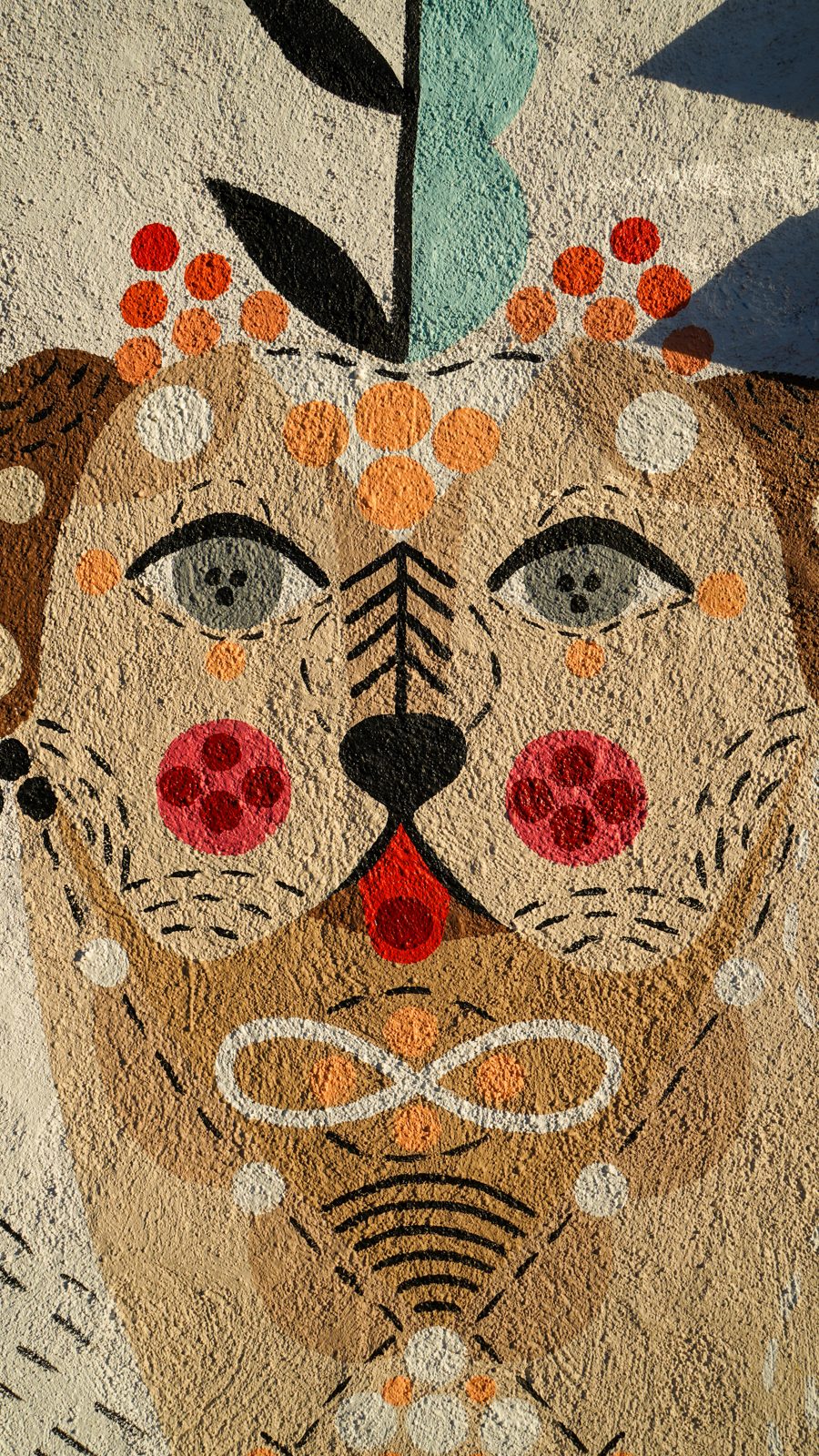 The folk-art dog face painted on the mural wall