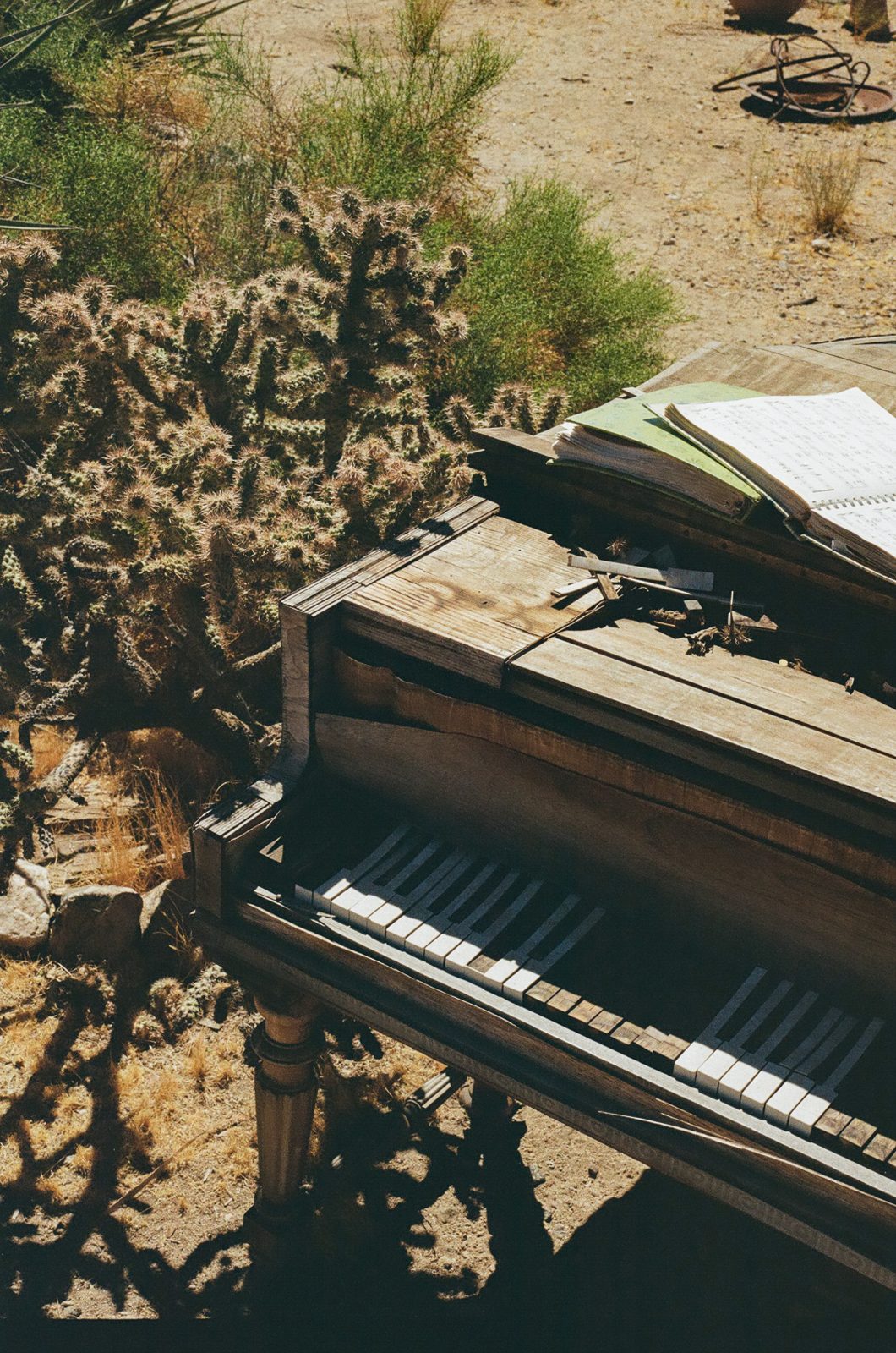The weathered outdoor piano beside a cholla cactus, sheet music open