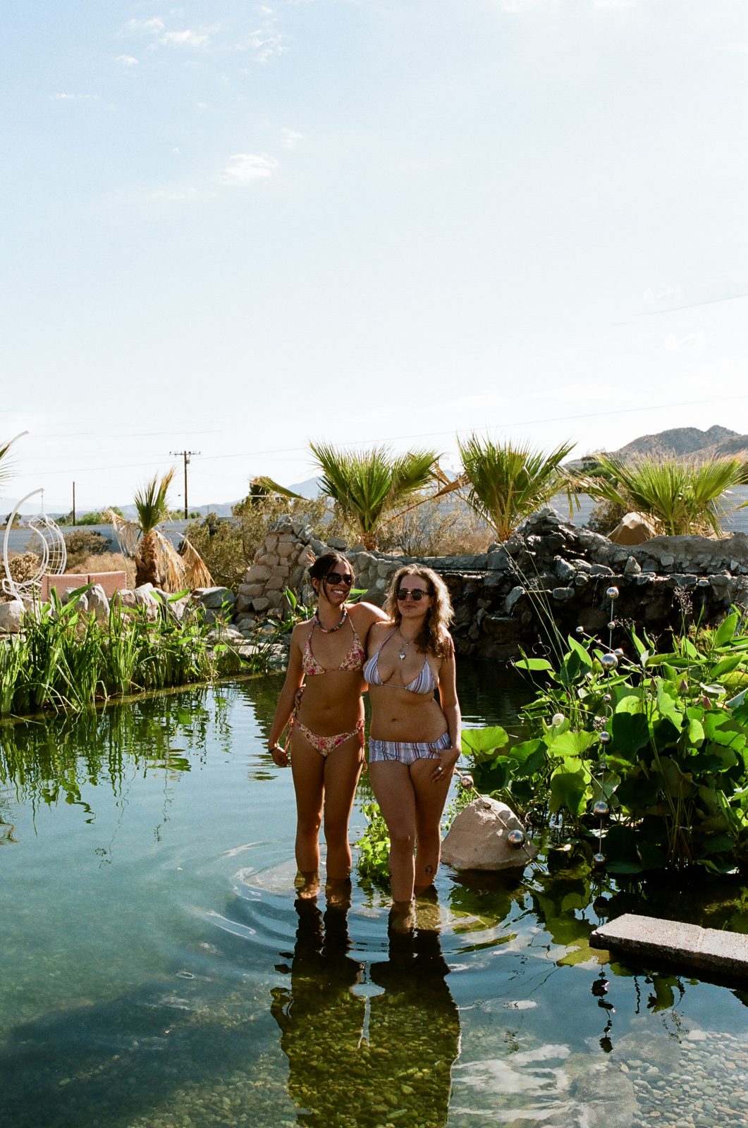 Two guests wading in the natural pool among the lily pads