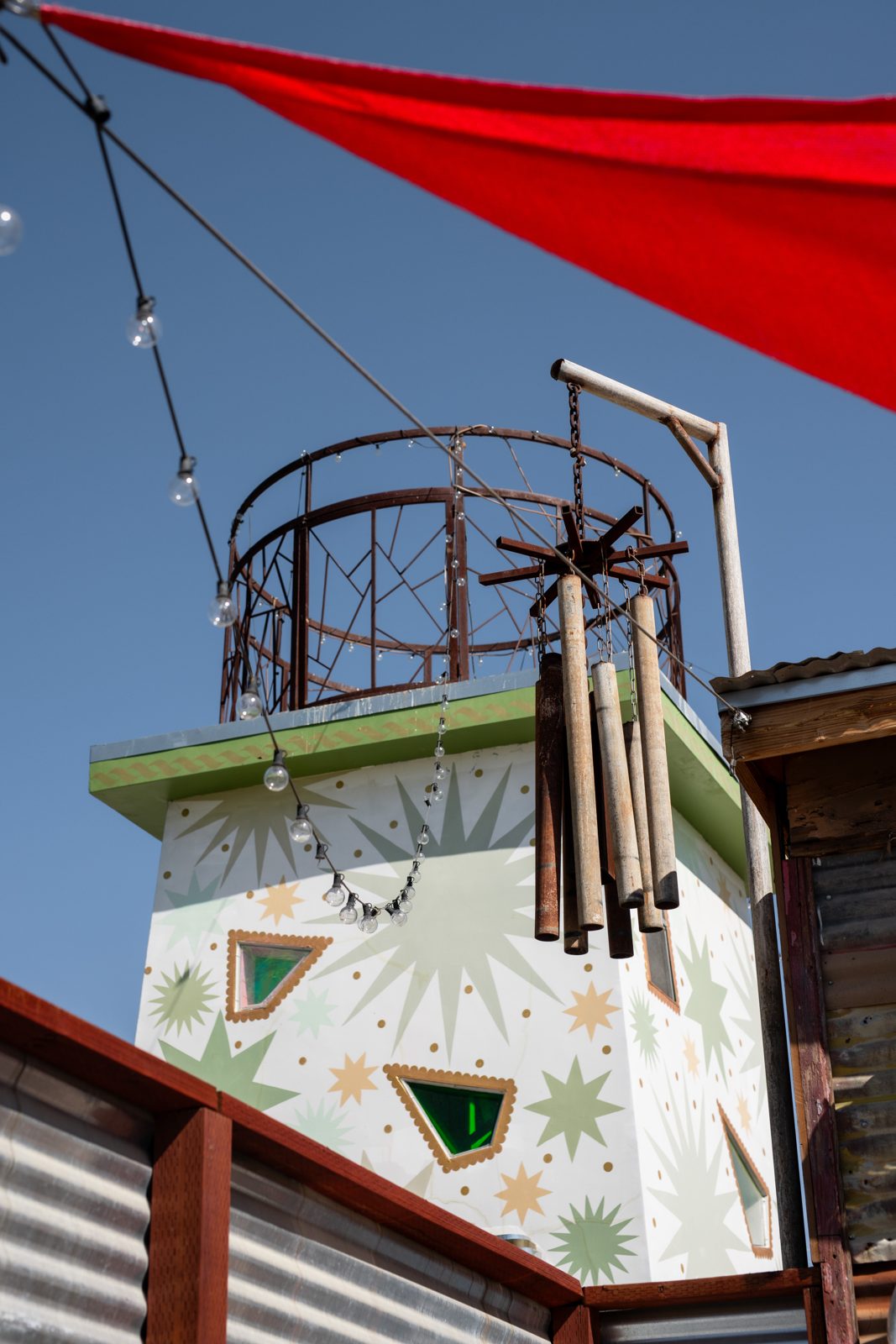Wind chimes on the star tower beneath a red shade sail