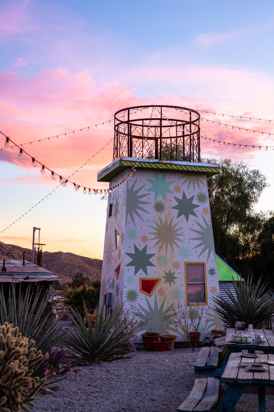 A painted structure covered in stars under a pink sunset